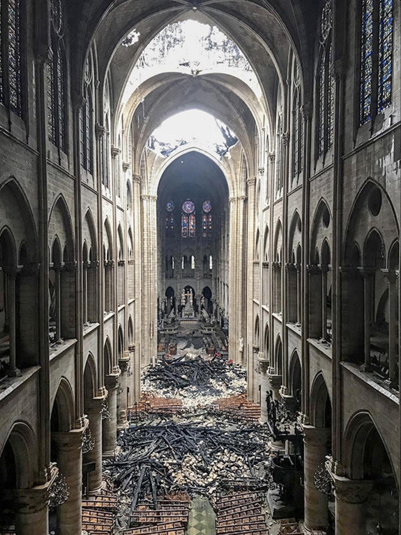 Photographie de la nef de la Cathdrale Notre Dame montrant les dégats provoqués par l'incendie du 15 avril 2019 et les vestiges de pierre et bois au sol.